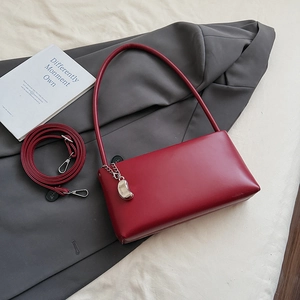 Detail view of a vintage red baguette bag with synthetic leather finish and silver chain decor