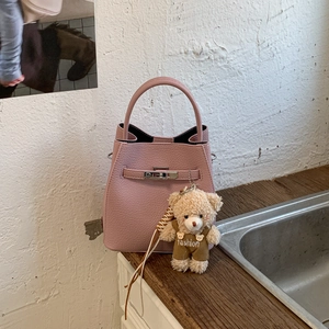 Detail of pink lychee leather bucket bag with silver twist lock and plush bear charm