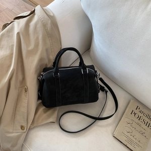 Detail view of a black Boston bag with embossed letters on a white fabric sofa