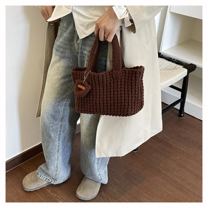 Detail of hand-made dark brown woven tote bag with a heart pendant and wooden tag