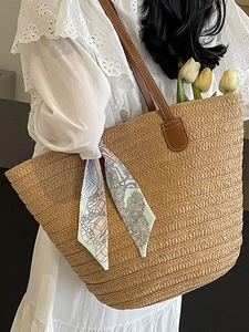 Women's straw woven tote bag with brown leather handles and decorative floral scarf for summer