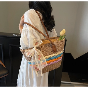 Detail of hand-woven straw tote bag with colored stripes and embroidered lace scarf