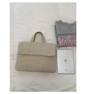 Detail of beige quilted laptop sleeve with soft padded fabric and square grid texture