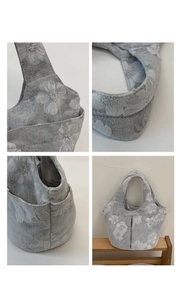 Detail view of grey floral embroidered tote bag showing wide handles and side pockets