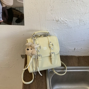 Detail view of cream vintage small square bag with leather straps and bear charm