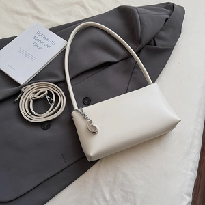 Detail of off-white faux leather baguette bag with silver fashion pendant on a blazer