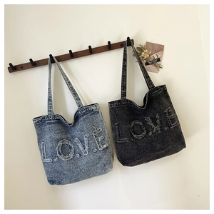 Detailed macro view of the vintage denim tote bag featuring frayed letter embroidery