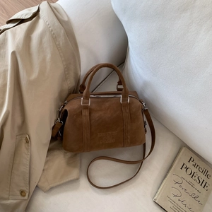 Brown nubuck Boston bag with embossed logo details on a beige trench coat