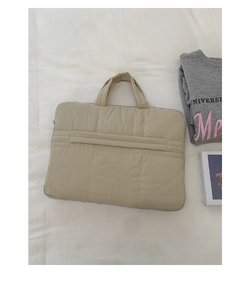 Detail of minimalist beige quilted laptop bag with soft padding and square stitching