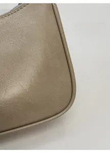 Gros plan sur la texture plissée et les coutures de ce sac à bandoulière beige minimaliste