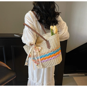 Detail of handwoven straw tote bag with colorful stripes and floral lace ribbon