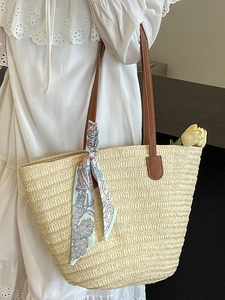 Large straw tote bag with brown leather handles and a floral scarf for summer beach vacation