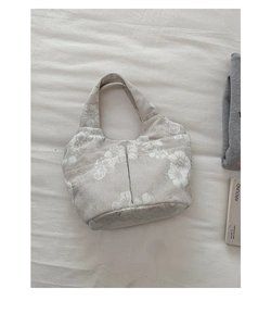 Flat lay of a large canvas tote bag with white floral prints and two front pockets