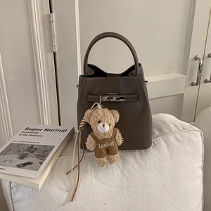 Detailed shot of dark brown lychee leather bucket bag with a cute plush bear charm