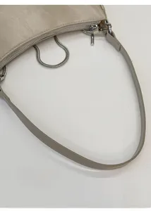 Détail de la bandoulière en cuir crème souple et de la fermeture éclair métallique du sac