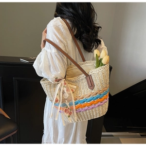 Detail of hand-woven straw tote with colorful stripes and lace bow on leather handle
