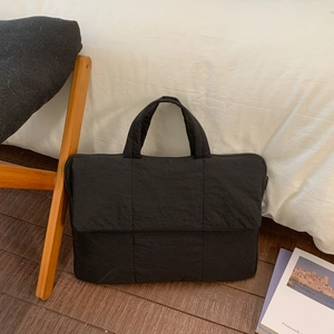 Detail of black quilted laptop bag showing padded stitching and durable handles