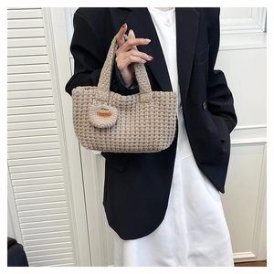Detail of woven knit handbag with heart charm and handmade tag on a honeycomb texture