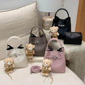Close-up of leather bucket bags with metal turn-lock closures and cute bear charms