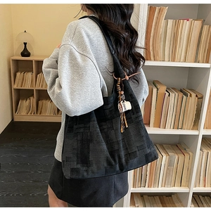 Macro detail of spacious black tote bag with gray jacquard pattern and coffee cup pendant