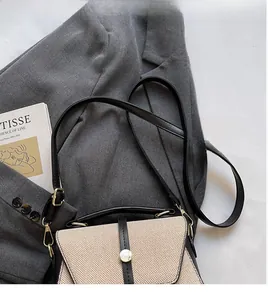 Détail d'un sac bandoulière patchwork minimaliste en tweed beige et cuir noir
