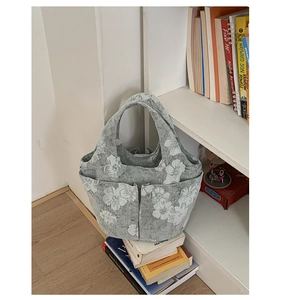 Close-up of a grey floral canvas tote bag featuring multiple functional exterior pockets