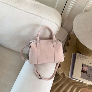 Close-up of pink Boston bag with embossed logo on soft cream-colored sofa backdrop