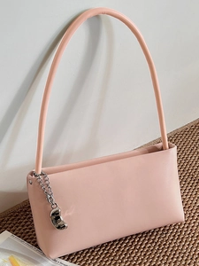 Pink faux leather baguette bag with silver chain charm on brown woven mat background