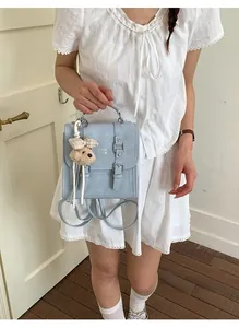 Detail of light blue square backpack with flap closure and cute plush bear charm