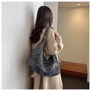 Detail of a large hobo shoulder bag with geometric jacquard pattern worn over a trench coat