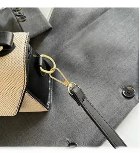 Détail de la boucle en métal doré sur le sac tissé crème avec bandoulière en cuir