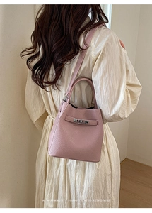 Detail view of pink pebble grain leather bucket bag with silver buckle and hand strap