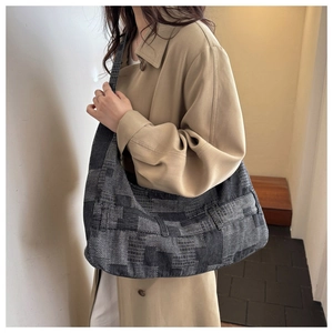Detail shot of the large textured hobo bag material and draped silhouette on a beige coat