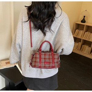 Detailed back view of vintage red plaid boston bag with leather trim and metal feet