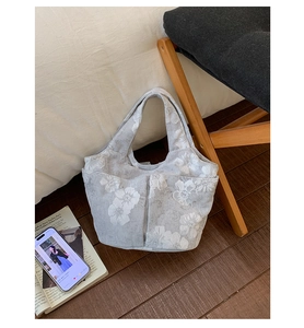 Detailed view of grey knitted bucket bag with white floral pattern and side pockets