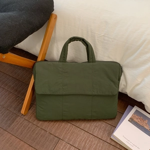 Minimalist olive green quilted laptop bag shown in a cozy home office setting