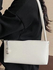 Minimalist white leather baguette bag with silver bean pendant shown on model shoulder
