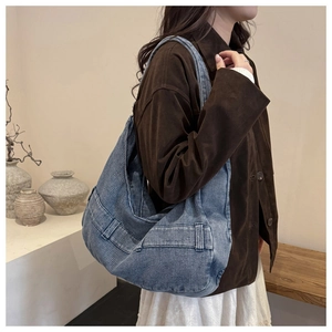 Close-up of blue corduroy tote bag with decorative buckle and side pocket detail