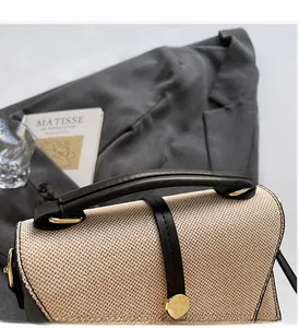 Détail de la poignée en cuir noir robuste et du tissu tissé beige sur le sac à main