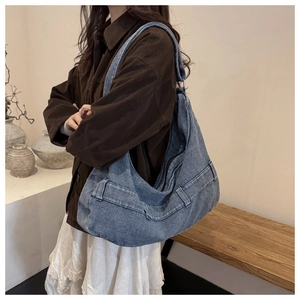 Detail of blue striped tote bag with leather buckle strap shown in a lifestyle setting