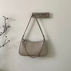 Détail du sac sous le bras beige avec chaîne argentée et petit logo élégant
