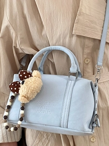 Light blue Boston bag with leather texture and bear charm shown on a model