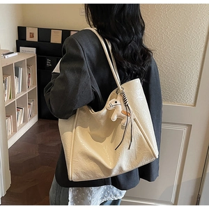 Chic cream tote bag with wrinkled texture and pony charm on a model in a library