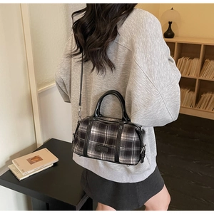 Chic plaid crossbody bag with black leather straps shown on a model in a cozy room