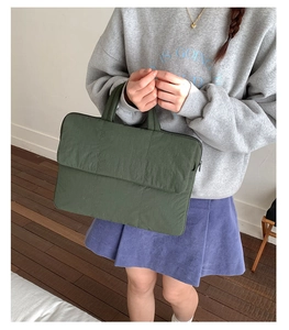 Detail view of dark green canvas tote bag featuring quilted flap and durable top handle