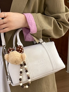 White leather Boston bag with plush bear charm and beaded chain on a model