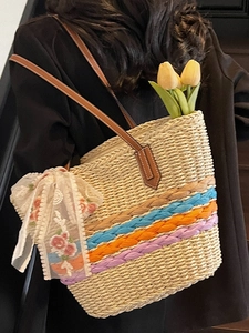Handwoven straw tote bag with colorful bands and brown leather straps for beach vacation