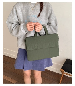 Detail view of dark green quilted laptop bag with shockproof vertical stitching and soft handles