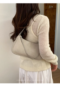 Sac bandoulière chic en cuir beige avec chaîne en métal sur une tenue en maille