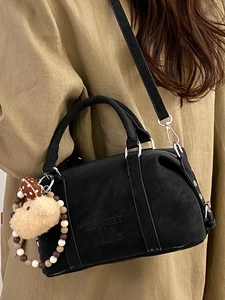 Fashionable black Boston bag with teddy bear charm and silver hardware shown with model